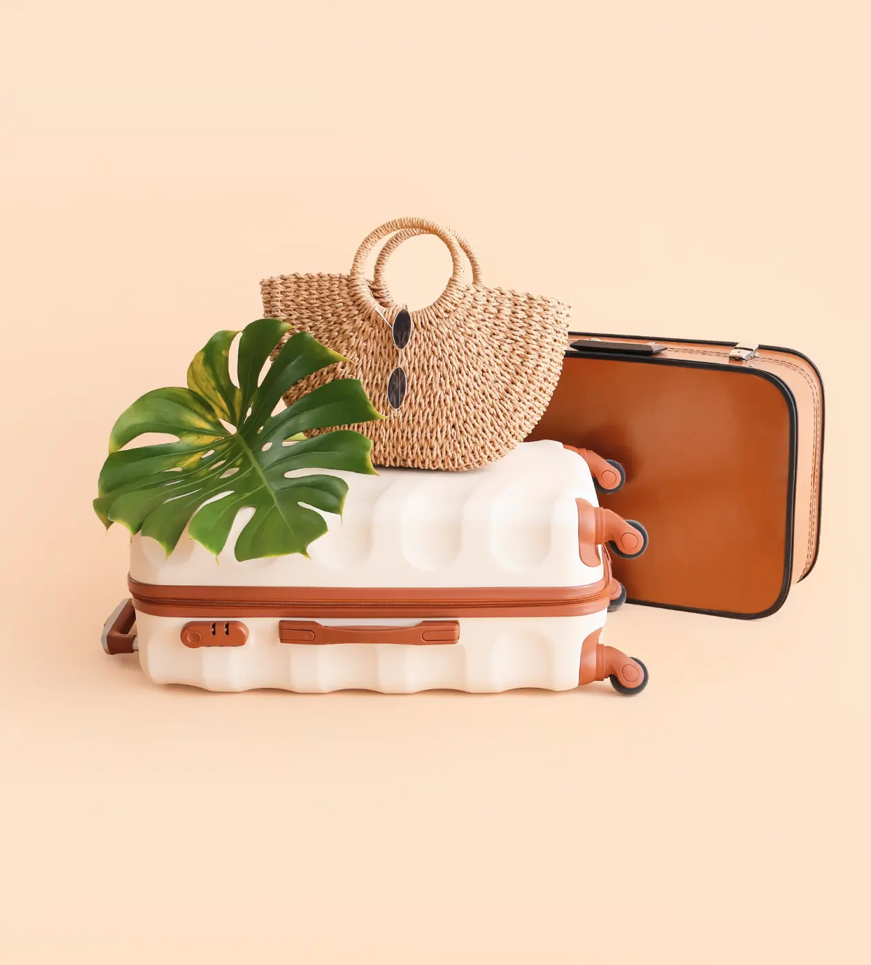 A collection of three suitcases alongside a bag featuring a palm leaf design, evoking a tropical travel theme.